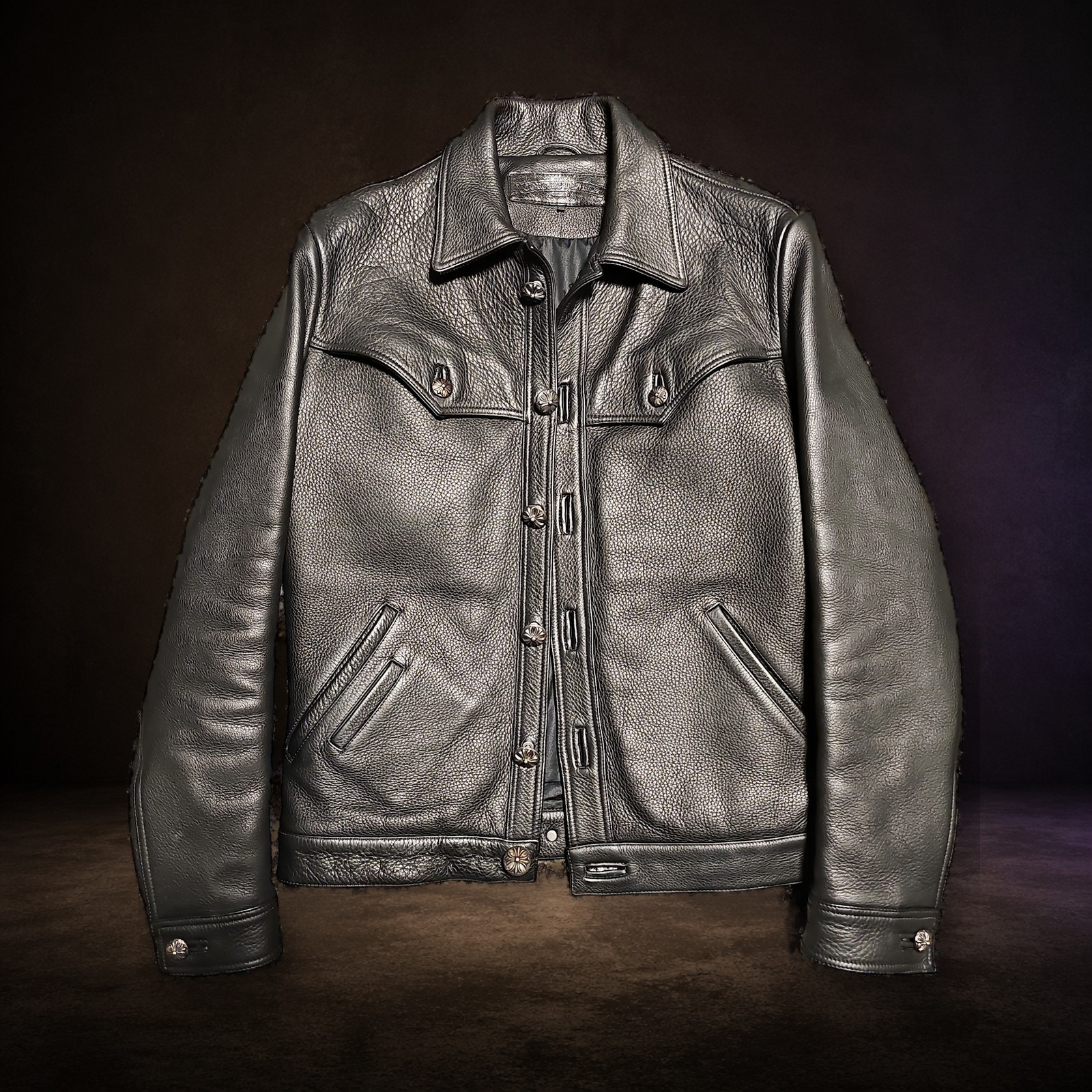 エスプレッソブラウンとチャコールの背景で撮影したCHROME HEARTS CLASSIC JEAN レザージャケット